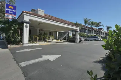 a parking lot with an arrow sign in front of a building at Welcome Inn Corona in Corona