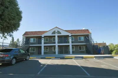 a building with a car parked in a parking lot at Welcome Inn Corona in Corona