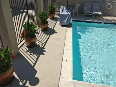 a swimming pool with potted plants next to a house at Burbank Inn and Suites in Burbank