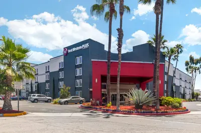a hotel with palm trees in front of a parking lot at Best Western Plus Commerce Hotel in Los Angeles