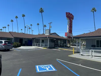 a parking lot in front of a motel with a handicapped sign at Hi-Way Host Motel in Pasadena