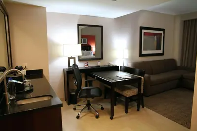 a hotel room with a desk and a couch at Embassy Suites Ontario - Airport in Ontario