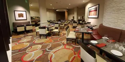a dining room with tables and chairs in a restaurant at Embassy Suites Ontario - Airport in Ontario