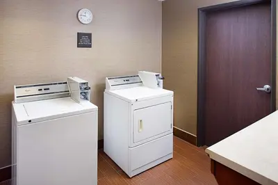 a laundry room with two machines and a clock on the wall at Hampton Inn & Suites Palmdale in Palmdale