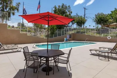 a table with a red umbrella next to a pool at Hampton Inn Norco/Corona in Norco
