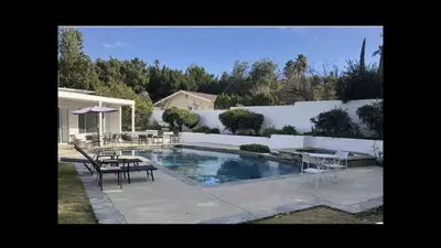 a swimming pool with tables and chairs next to a fence at Beautiful 4BD and 3BA Pool Jacuzzi Vacation Home in Los Angeles