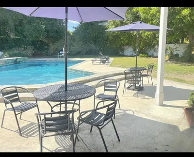 a table and chairs with umbrellas next to a pool at Beautiful 4BD and 3BA Pool Jacuzzi Vacation Home in Los Angeles