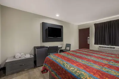 a hotel room with a bed and a desk and a tv at Rodeway Inn San Bernardino - Colton in San Bernardino