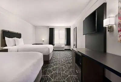 a hotel room with two beds and a flat screen tv at La Quinta by Wyndham Hesperia Victorville in Hesperia