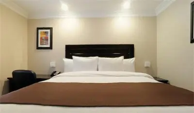 a bedroom with a large bed and a chair at Raincross Hotel Riverside in Riverside