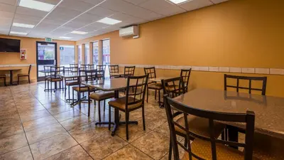 a dining room with tables and chairs and yellow walls at SureStay Hotel by Best Western Tehachapi in Tehachapi