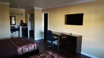 a hotel room with a bedroom with a desk and a bed at Anaheim Astoria Inn & Suites in Anaheim