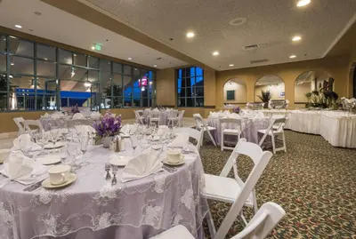 a banquet hall with white tables and white chairs at Grand Vista Hotel in Simi Valley