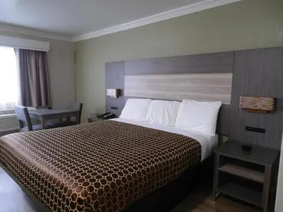 a hotel room with a large bed with a wooden headboard at Americas Best Value Inn-Rialto in Rialto