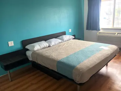 a bedroom with a bed with a blue wall at Motel 6-Norwalk, CA in Norwalk