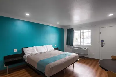 a bedroom with a large bed with a blue wall at Motel 6-Norwalk, CA in Norwalk