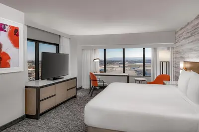 a hotel room with a bed and a desk with a television at Hilton Los Angeles Airport in Los Angeles