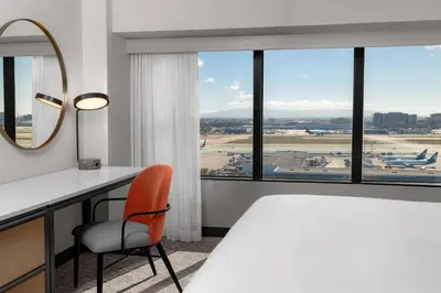 a room with a desk and a mirror and an airport at Hilton Los Angeles Airport in Los Angeles