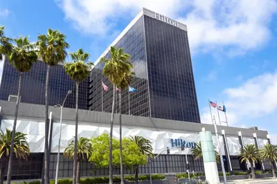 a tall building with palm trees in front of it at Hilton Los Angeles Airport in Los Angeles