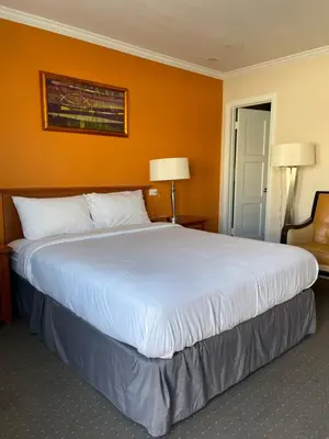 a large bed in a hotel room with an orange wall at Howard Johnson by Wyndham Ridgecrest, CA in Ridgecrest