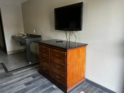 a room with a tv and a dresser with a sink at Sunpark Inn & Suites in San Bernardino