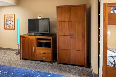 a room with a television on a wooden dresser at Anaheim Portofino Inn & Suites in Anaheim