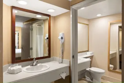 a bathroom with a sink and a toilet and a mirror at Anaheim Portofino Inn & Suites in Anaheim