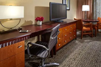 a hotel room with a desk with a television and a chair at Anaheim Portofino Inn & Suites in Anaheim
