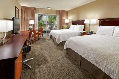 a hotel room with two beds and a flat screen tv at Anaheim Portofino Inn & Suites in Anaheim