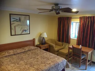 a bedroom with a bed and a chair and a table at Bayshore Inn Ventura in Ventura