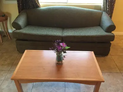 a coffee table with a vase of flowers on a couch at Bayshore Inn Ventura in Ventura