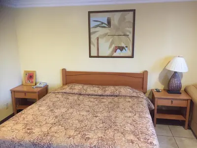 a bedroom with a bed with two nightstands and two tables at Bayshore Inn Ventura in Ventura