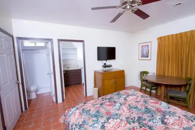 a bedroom with a bed and a desk and a table at Mission Bell Motel in Ventura