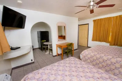 a hotel room with two beds and a desk and a television at Mission Bell Motel in Ventura