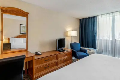 a hotel room with a bed and a desk with a mirror at Clarion Hotel Anaheim Resort in Anaheim