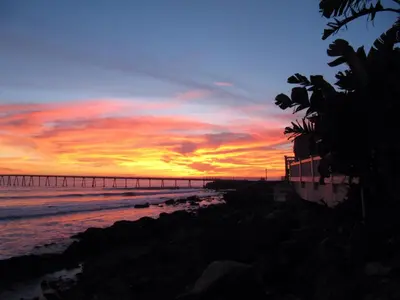 a sunset on the beach with a pier in the background at Cliff House Inn in Carpinteria