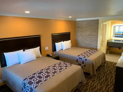 a hotel room with two beds and a bathroom at Ontario Inn & Suites in Montclair
