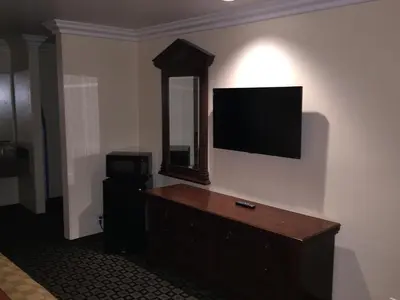 a room with a television on a wall with a dresser at Ontario Inn & Suites in Montclair