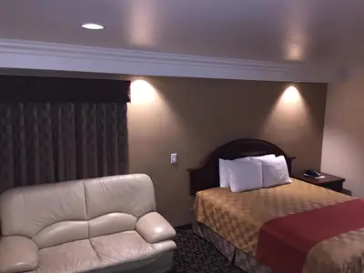 a hotel room with a bed and a couch at Ontario Inn & Suites in Montclair