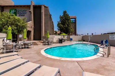 a swimming pool with tables and chairs and a building at Holiday Inn Express & Suites Camarillo by IHG in Camarillo
