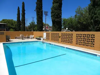 a large swimming pool with a fence and trees at American Inn in Ontario