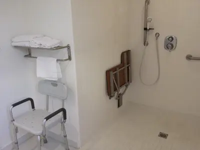 a bathroom with a shower and a chair in it at Travelers Beach Inn in Ventura