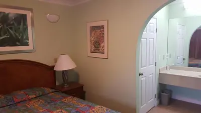 a bedroom with a bed and a sink and a mirror at Flamingo Inn Long Beach in Long Beach