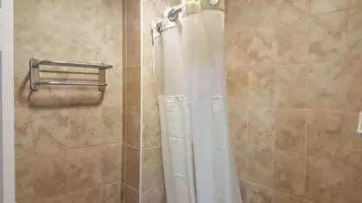 a shower with a white shower curtain in a bathroom at Flamingo Inn Long Beach in Long Beach