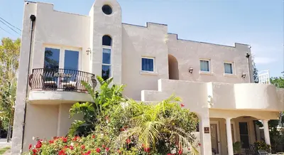 a white house with a balcony and some flowers at Santa Paula Inn in Santa Paula