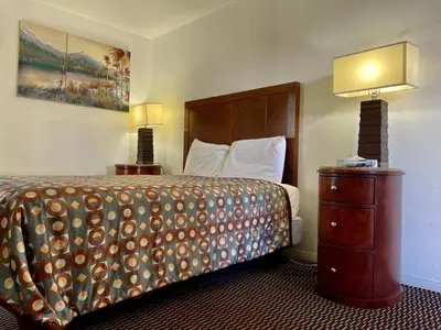 a hotel room with a bed and a dresser and lamps at Desert Inn in Mojave