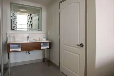 a bathroom with a door and a sink and a mirror at Hampton Inn & Suites Sherman Oaks in Sherman Oaks