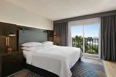 a bedroom with a large bed and a large window at Embassy Suites by Hilton Los Angeles Downey in Downey