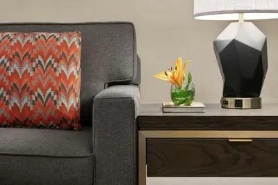 a lamp on a table next to a chair with a vase of flowers at Embassy Suites by Hilton Los Angeles Downey in Downey