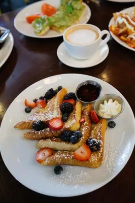 a plate of french toast with fruit on a table at Padre Hotel in Bakersfield